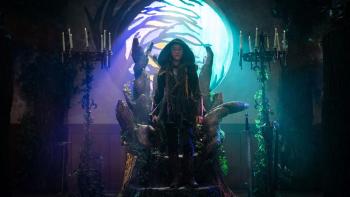 Robin and the Hoods: A young girl stands wearing a hood with a bow and arrows strapped to her back in front of a wooden throne
