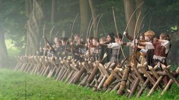 Robin and the Hoods: A group of kids stand in line wearing Medieval costumes and holding bows and arrows