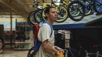 Roofman Movie: Jeffrey (Channing Tatum) explores a toy store, eating something from a bag while in the bike section