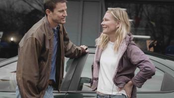 Roofman Movie: Jeffrey (Channing Tatum) leans on a car while chatting with Leigh (Kirsten Dunst) in a parking lot