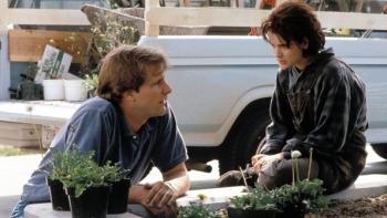 Welcome Home, Roxy Carmichael: Man kneeling by plants talking to seated teenage girl near a truck