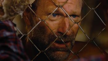 Rumble Through the Dark Movie: Jack "The Butcher" Boucher (Aaron Eckhart), a bloody cut on his nose, peers through a chain-link fence