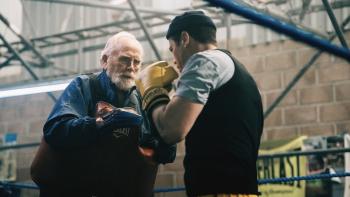 Salvable: An older man holds some boxing pads while a younger man prepares to hit them