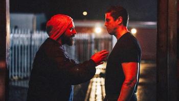 Salvable: Two men face each other at night under red lighting; one wears a hoodie and gestures, while the other stands still with a serious expression