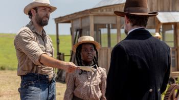 Sarah's Oil movie: Zachary Levi stands next to Naya Desir-Johnson while holding out a paper to a man
