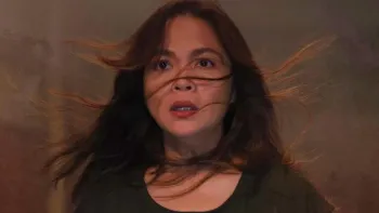 Scarecrow movie: Filipino woman with long black hair flying around her face looks forward in a dark place