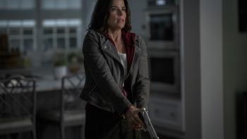 Scream 7 Movie: Looking shocked and tense, Sidney (Neve Campbell) clutches a gun with both hands, ready for anything