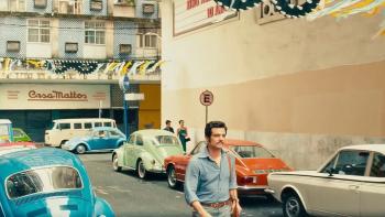 The Secret Agent movie: Wagner Moura walks through the streets of Brazilian city Recife with brightly colored cars parked either side of the road