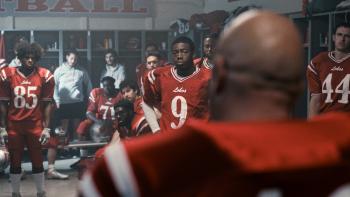 The Senior Movie: Mike, seen from the back, appears to be saying something to his teammates in the locker room