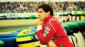Senna: Ayrton Senna looking over a race track wearing a red racing suit next to a yellow helmet