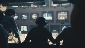 September 5 Movie: The control room crew, seen from behind, loos at a bank of monitors