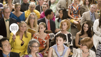 Sex and the City: The Movie: Samantha holds up an auction sign in a crowd, sitting next to Carrie, Charlotte, Miranda