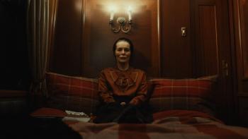 She Will: Alice Krige sits on a large sofa in a dimly lit space.