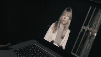 Shelby Oaks Movie: Riley's concerned face looks out from a video being watched by someone on a laptop
