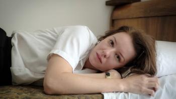 Irina Starshenbaum lays down on a bed wearing a white top and dark bottoms