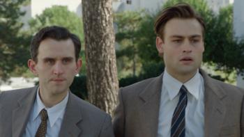 Shoshana: Harry Melling and Douglas Booth stand together wearing suits and ties, looking concerned