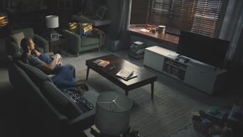 Silent Night Movie: Seen from above and behind, Brian Godlock (Joel Kinnaman) and his wife, Saya (Catalina Sandino Moreno), hold each other on the couch in a darkening living room