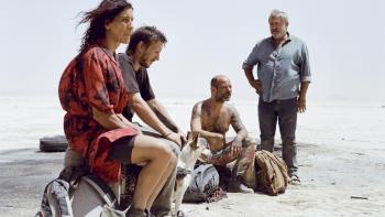 Sirāt: Ravers sitting on rocks in dessert.