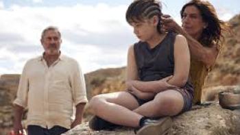 Sirāt: Father watches woman brain and shave son's hair.