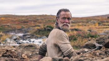 Sisu Movie: Aatami Korpi peeks out of a hole he's dug looking for gold with an alarmed expression on his face