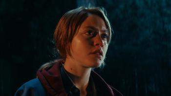 Watch the Skies: A White teenage girl looks worried as she stares out into the darkness