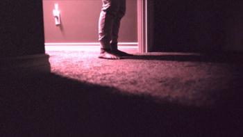 Skinamarink Movie: A child's feet are seen in a doorway leading into a dark room