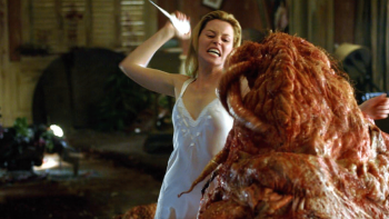 Slither movie: Starla in a white negligee holds up a sharp pick as it to strike a huge flesh-colored blob alien