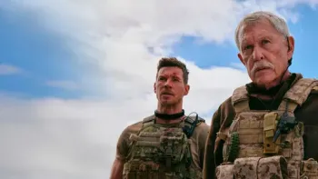 Sniper—No Nation: Two White men in military tactical vests stand with a blue sky above them