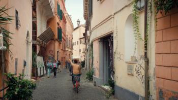 Solo Mio movie: A couple rides a tandem bicycle down a cobblestone road through Rome