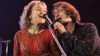 Song Sung Blue movie: Kate Hudson and Hugh Jackman sing into a microphone while performing as their Neil Diamond tribute band