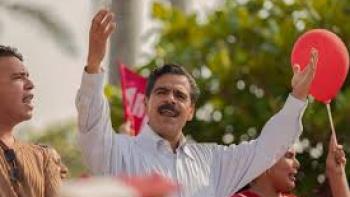 Son-in-Law Movie: Man in white shirt gestures passionately at outdoor rally.
