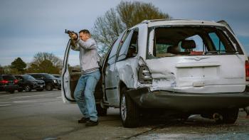 Sovereign Movie: Jerry Kane, taking cover behind the open door of his car, prepares to fire an assault rifle