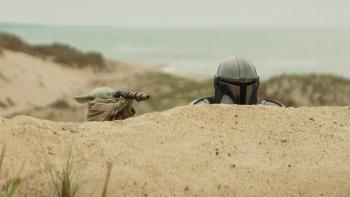 Star Wars: The Mandalorian and Grogu movie: The Mandalorian hides behind a rise in the ground, Grogu next to him
