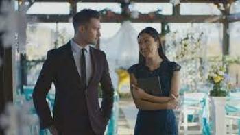 Stars Fell Again Movie: James Maslow wears a suit at a wedding while looking a woman holding a clipboard