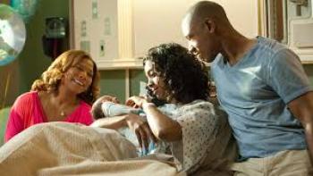 Steel Magnolias: Woman holding baby in hospital bed, two people beside her smiling.