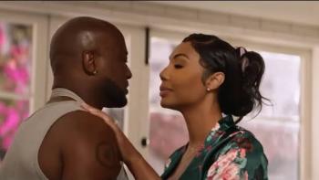 Stepfather Movie: Black couple embracing in a brightly lit room, window with pink flowers in the background.