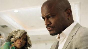 Stepfather Movie: Taye Diggs in a suit looking serious, Tamar Braxton in background watching, indoors.