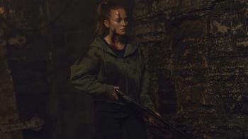 The Strangers: Chapter 3 Movie: Maya, injured and covered in blood, carries a shotgun into a kind of brick-walled cellar