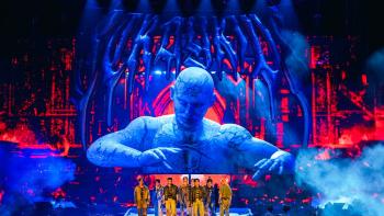 Stray Kids: The dominATE Experience movie: The Stray Kids stand on stage with their logo projected on screen