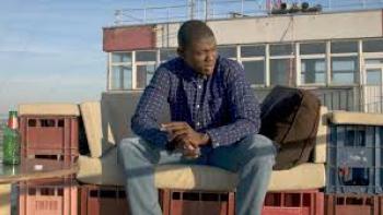 Street Flow Movie: Black man in long-sleeved shirt sits outside