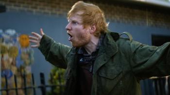 Sumotherhood: Ed Sheeran in a park wearing a green coat with his arms outstretched