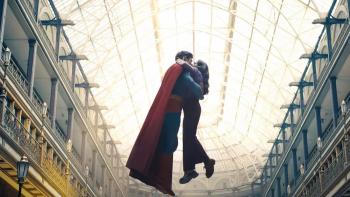Superman movie: Superman, in his blue costume and red cape, embraces Lois while floating in a glass-roofed arcade