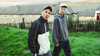 Sweet Sixteen: Two young White male teens in casual wear try to look cool and threatening as they walk through a housing estate