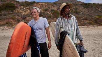 Sweet Dreams: Johnny Knoxville and Gate hold surfboards on a beach