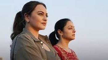 System movie: Two Indian women gazing in the distance against a clear sky.