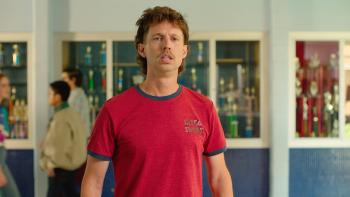 Tapawingo movie: Jon Heder stands in a high school wearing a red shirt, looking off camera