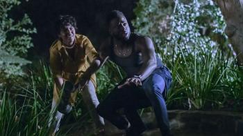 The Blackening Movie: Antoinette Robertson and Sinqua Walls crouch outside as they try to escape the killer