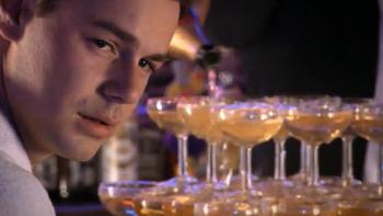 The Business: Man looking at a champagne tower in a dimly lit setting