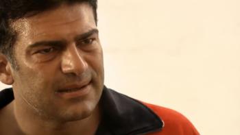 The Business: Man in a red jacket with a concerned expression against a plain background