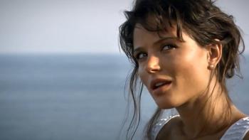 The Business: Woman by the sea with a thoughtful expression, wearing a white top